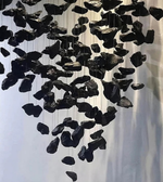 Black stone sculpture hanging against a white background