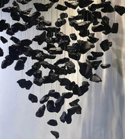 Black stone sculpture hanging against a white background