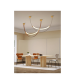 Modern chandelier hanging above a dining table with chairs in a minimalistic room.