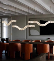 Modern dining room with wavy pendant lights and brown chairs.