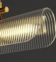 Close-up of a ribbed glass pendant light with gold fixture on a dark background