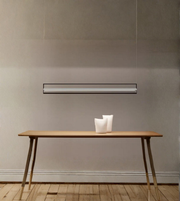 Modern pendant light fixture hanging above a wooden table with decorative items.