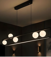 Modern pendant light fixture with four round lights on a dark ceiling.