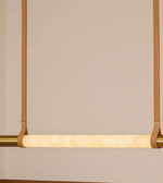 Modern pendant light with gold frame and white bulb on a beige background