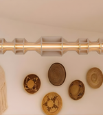 Decorative wall piece with a metallic rod and woven baskets on a beige background