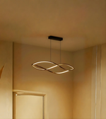 Modern pendant light hanging from a ceiling in a softly lit room.