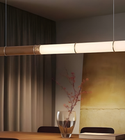 Modern pendant light fixture hanging above a table with a vase and books in a room.