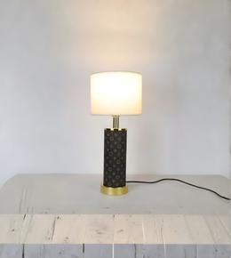 Table lamp with a textured black base and gold accents on a light wooden surface.