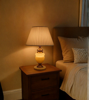 Lamp on a nightstand next to a bed with soft lighting