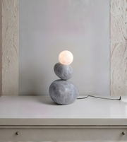 Modern table lamp with two stacked stone-like bases on a white surface.