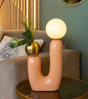 Modern pink lamp with round bulb on a table in a living room setting