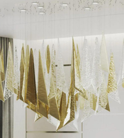 Decorative wall art with gold and white abstract designs on a white wall.