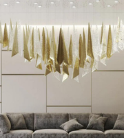 Modern interior with a decorative wall art featuring gold and white elements above a gray sofa.