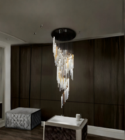 Modern chandelier hanging in a room with dark walls and a textured ottoman.