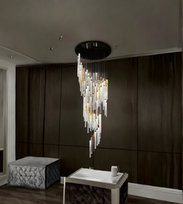 Modern chandelier hanging in a room with dark walls and a textured ottoman.