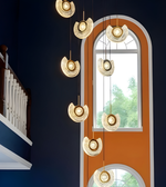 Modern chandelier hanging in a room with a window and staircase.