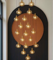 Modern chandelier with multiple hanging lights against a decorative wall.