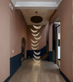 Decorative hanging lights in a hallway with pink walls and a staircase.