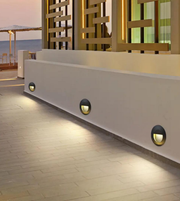 Modern outdoor setting with a white wall and decorative metal grid, featuring wall-mounted lights.
