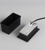 Black rectangular box with a metallic component on a gray background