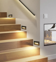 Wooden staircase with built-in lighting and a fireplace in the background.