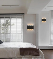 Modern bedroom with a bed, wall lights, and a window with blinds.