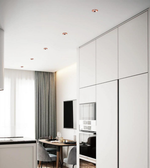 Modern kitchen with white cabinetry, a small dining area, and a television.