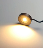 Small round light fixture casting a warm glow on a gray background