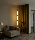 Modern living room with a beige armchair, pendant light, and decorative elements.