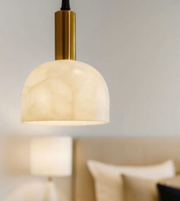 Modern pendant light with marble shade and gold fixture in a room setting.