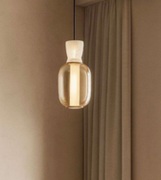 Pendant light with a clear glass shade against a brown curtain background