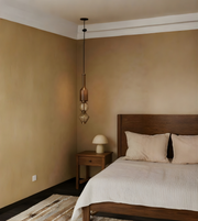 Bedroom with wooden bed, beige walls, and pendant light fixture.