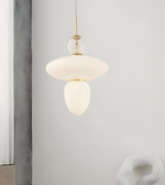 Modern pendant light with white glass shade and gold fixture against a neutral background