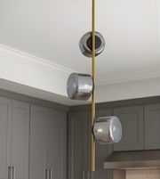Modern pendant light fixture with glass shades and gold accents in a kitchen setting.