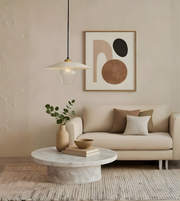 Modern living room with a beige sofa, marble coffee table, abstract art, and pendant light.