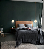 Modern bedroom with dark green walls, a bed with gray bedding, and pendant lights.