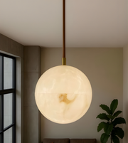 Spherical pendant light hanging in a room with a window and plant in the background