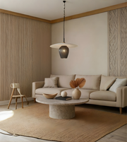 Modern living room with beige sofa, round stone coffee table, and decorative elements.