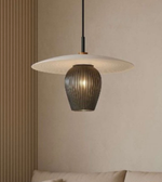 Modern pendant light with a textured shade and ribbed base against a neutral wall.