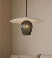 Modern pendant light with a textured shade and ribbed base against a neutral wall.