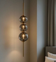 Modern pendant light with three glass shades in a room setting.