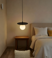 Modern pendant light hanging above a bed in a bedroom setting