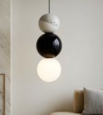 Modern pendant light with three spherical shades in a minimalistic room.