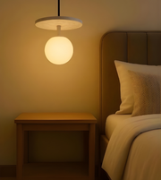 Bedroom with a bedside table and hanging lamp casting a warm glow.