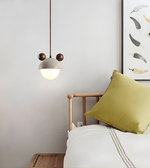 Bedroom interior with a green pillow on a bed, a pendant light, and wall art.