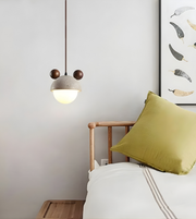 Bedroom interior with a green pillow on a bed, a pendant light, and wall art.