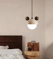 Modern pendant light above a wooden nightstand with a suitcase in a bedroom setting.
