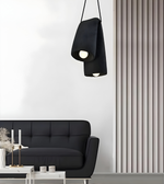 Modern living room with a black sofa and pendant light against a white wall.