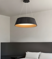Black pendant light hanging above a bed in a bedroom setting