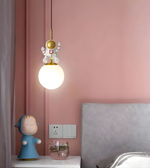 Pendant light with decorative character against a pink wall